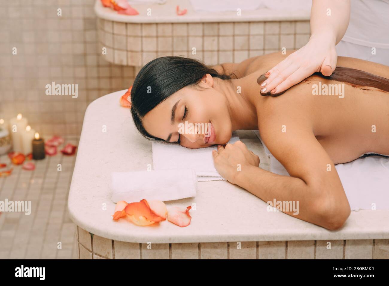 Bella donna che gode procedura di confezionamento del cioccolato. La procedura della maschera corpo al cioccolato nutre la pelle con vitamine, minerali e antidepressivi Foto Stock