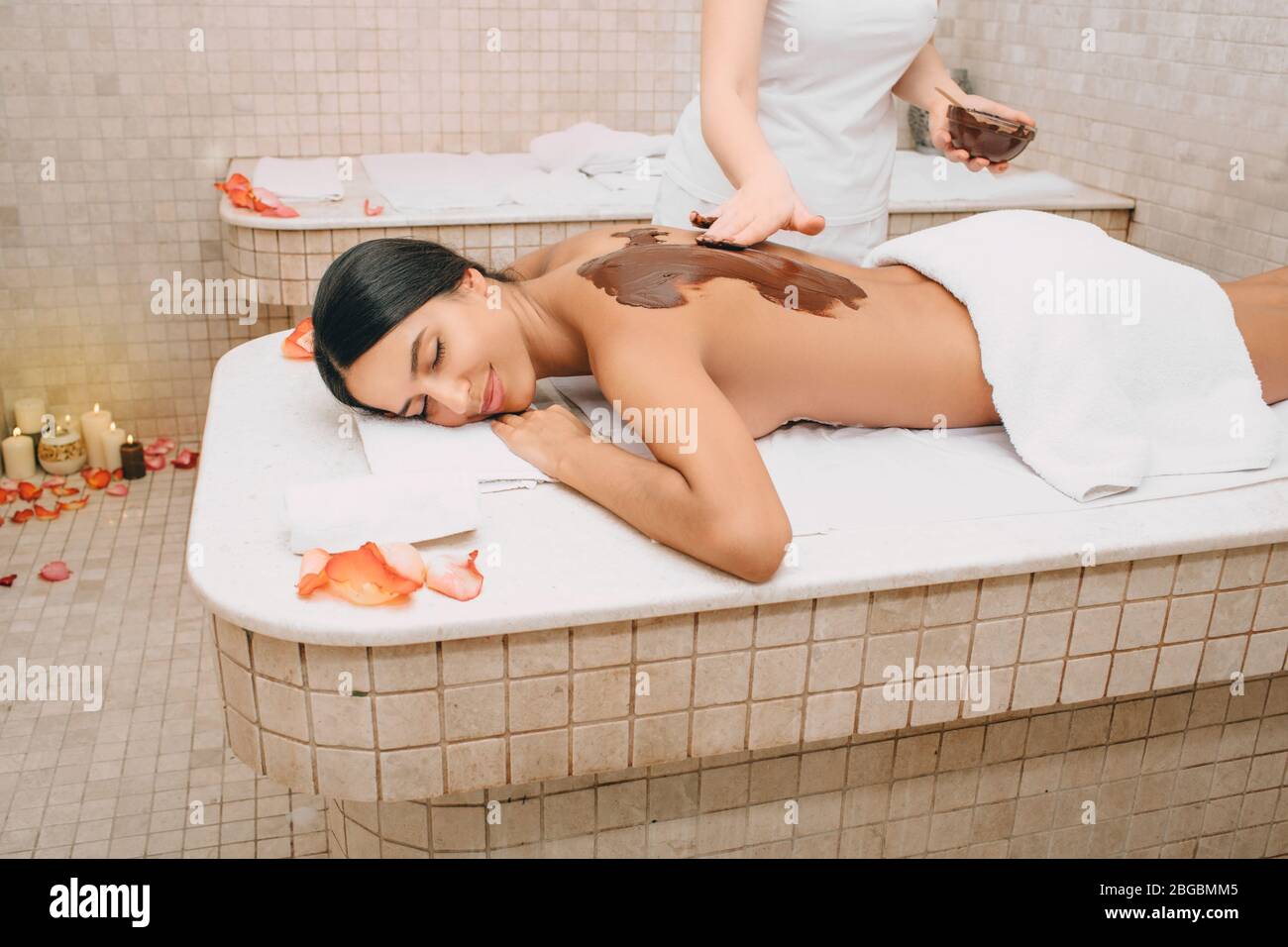 Bella donna che gode procedura di confezionamento del cioccolato. La procedura della maschera corpo al cioccolato nutre la pelle con vitamine, minerali e antidepressivi Foto Stock