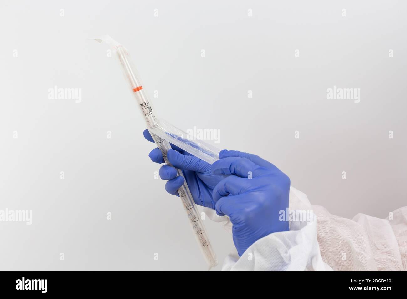 Donna medico in indumenti protettivi apertura di un tubo medico sterile, sfondo bianco, virus, protezione pandemica Foto Stock