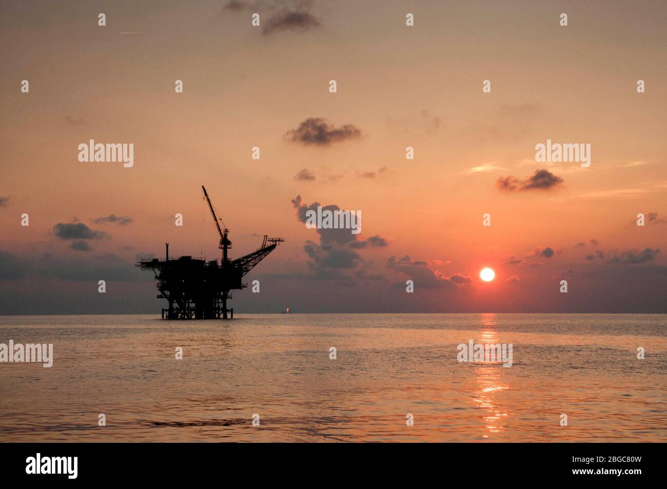 perforazione di piattaforme petrolifere in mare al tramonto Foto Stock