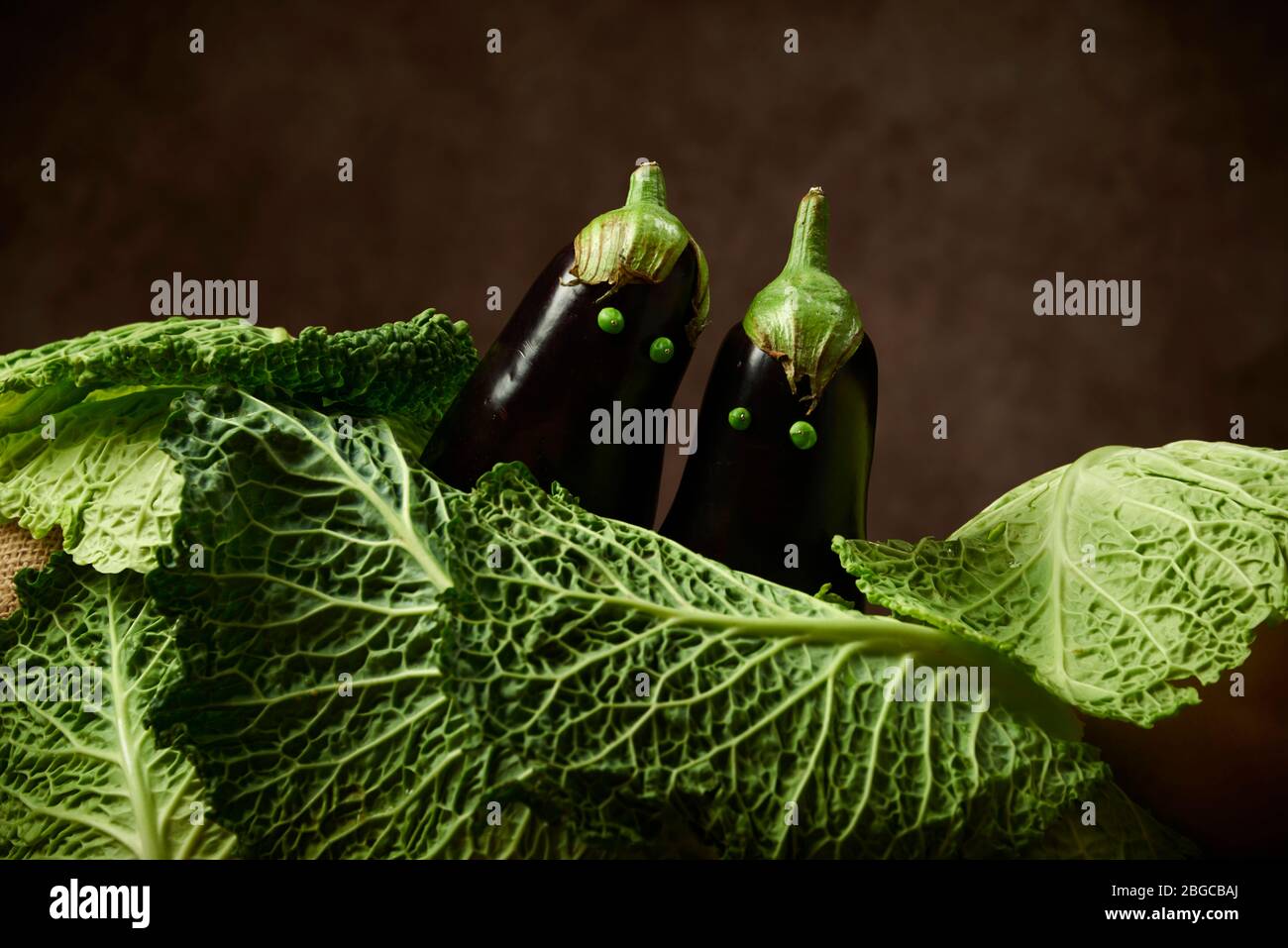 Verdure in studio di fotografia. Divertente posa di verdure art. Melanzane uovo-pianta posto come bambini circondati da cavolo . Foto Stock