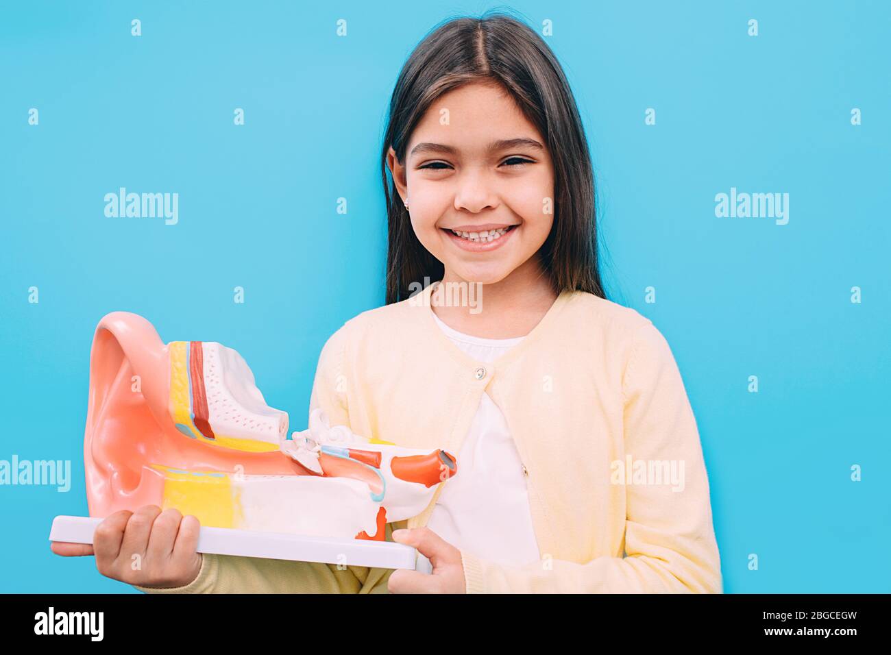 Ragazza mista razza che tiene modello di orecchio umano. Test dell'udito nei bambini Foto Stock