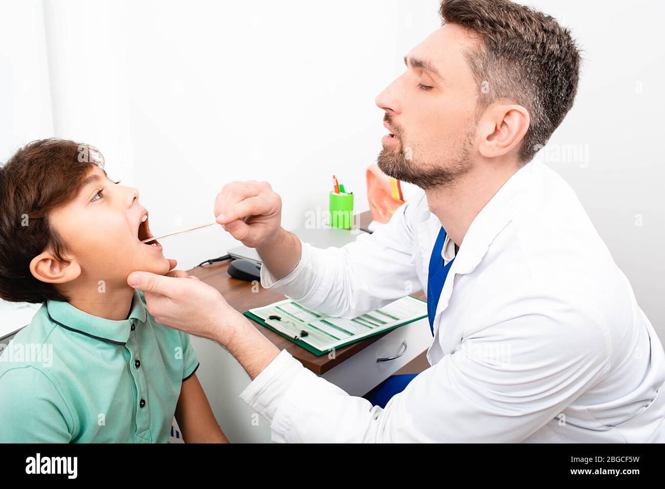 il pediatra controlla la gola di un ragazzo. Tonsillite, infiammazione delle tonsille, bambino con bocca aperta Foto Stock