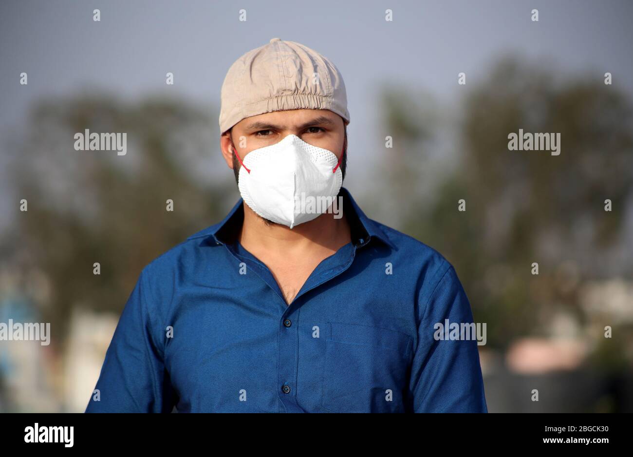 Giovani uomini di etnia indiana in piedi all'aperto e lui coprire il suo viso con maschera di inquinamento per la forma di protezione dai virus Foto Stock