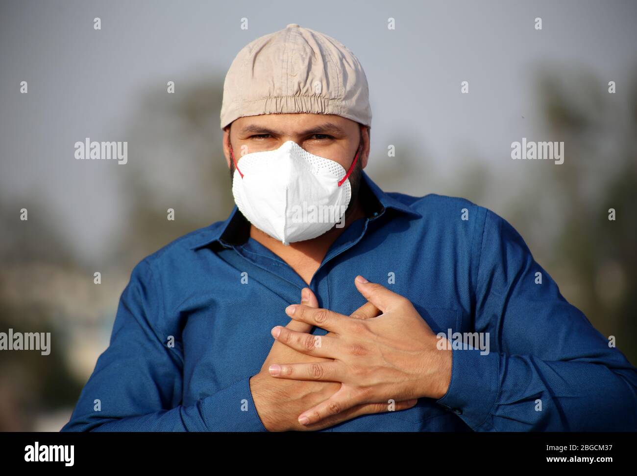 Giovani uomini di etnia indiana che ricoprono il suo viso con maschera di inquinamento per la protezione contro Coronavirus. Foto Stock