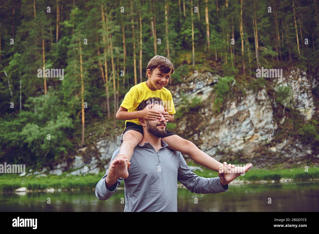 Padre e figlio sorridono mentre trascorrono il tempo insieme. Il ragazzino si siede sul collo del padre Foto Stock