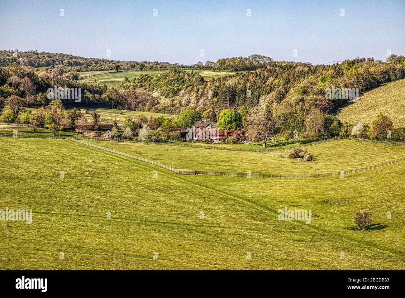 Campagna inglese, con colline sullo sfondo, prati e un cottage lontano Foto Stock