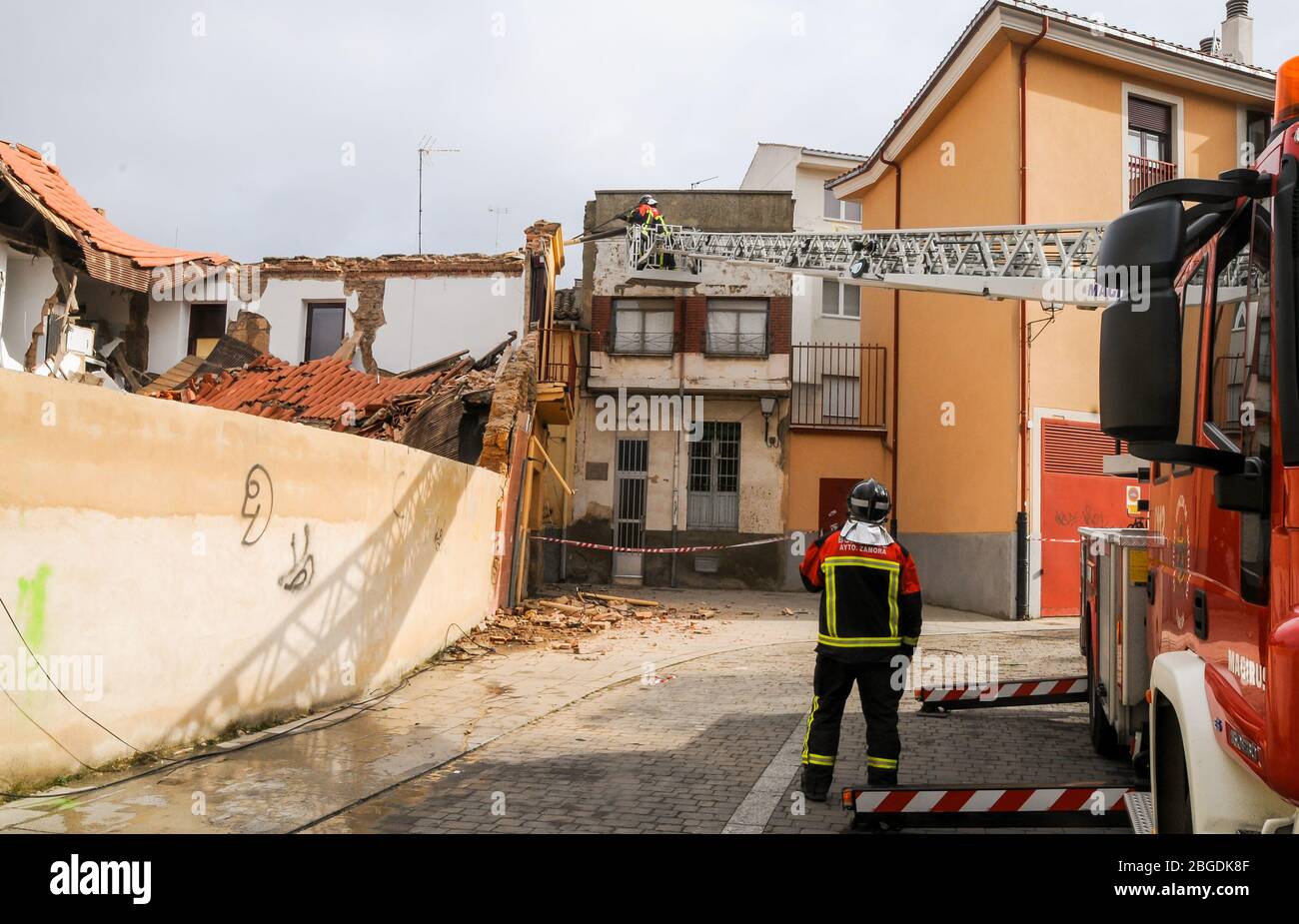 Pompieri montati su una gru per camion antincendio sulla strada che lavora su un impianto collassato Foto Stock