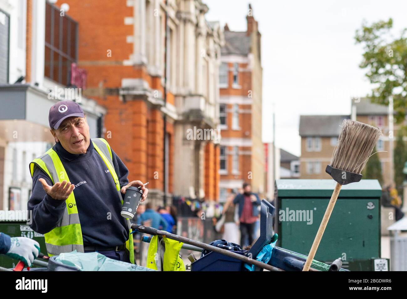 Un pulitore stradale in una giacca ad alta visibilità in Windrush Square, Brixton, Londra Foto Stock