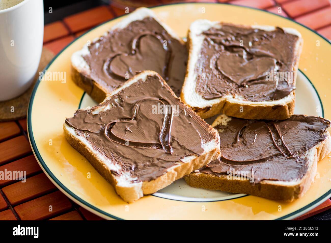 Fette di pane o pane tostato con crema di cioccolato e tazza di caffè e latte, forma a cuore Foto Stock