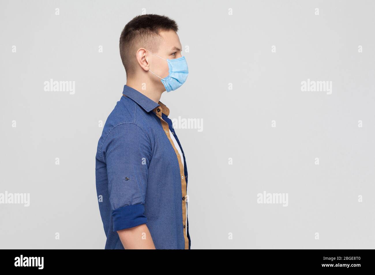 Vista laterale, protezione contro le malattie contagiose, coronavirus. Uomo con maschera igienica per prevenire infezioni, malattie respiratorie trasmesse dall'aria, Covid-201 Foto Stock