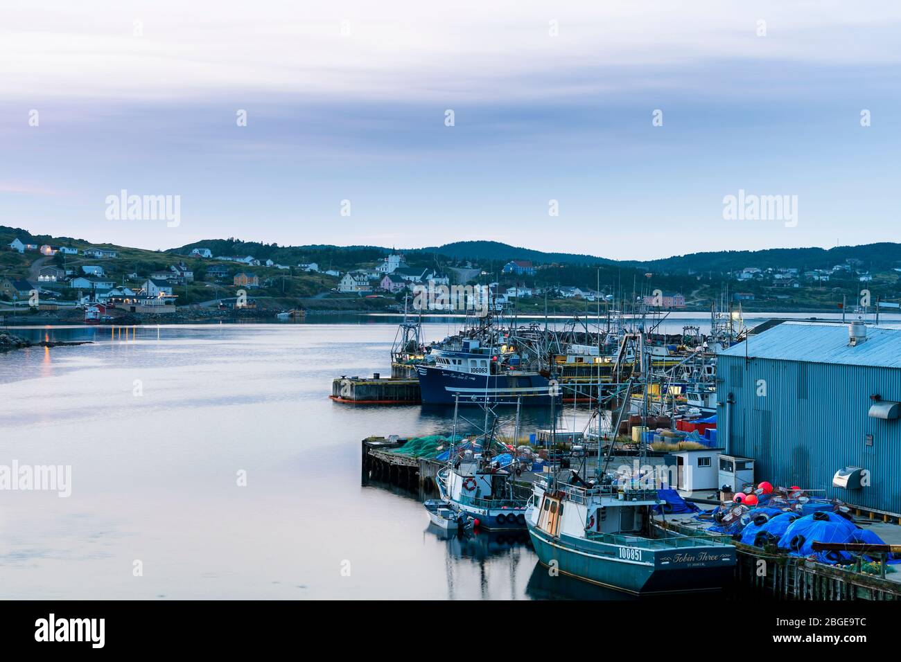 Primo colpo blu ora del porto di Twillingate con acque calme e il piccolo villaggio sullo sfondo, Terranova, Canada Foto Stock