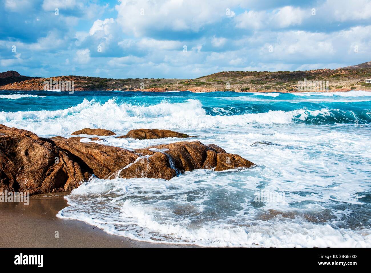 Vista sulle formazioni rocciose e sul mare Mediterraneo, con forte rigonfiamento, sulla spiaggia di la Marinedda, a Isola Rossa, Sardegna Foto Stock