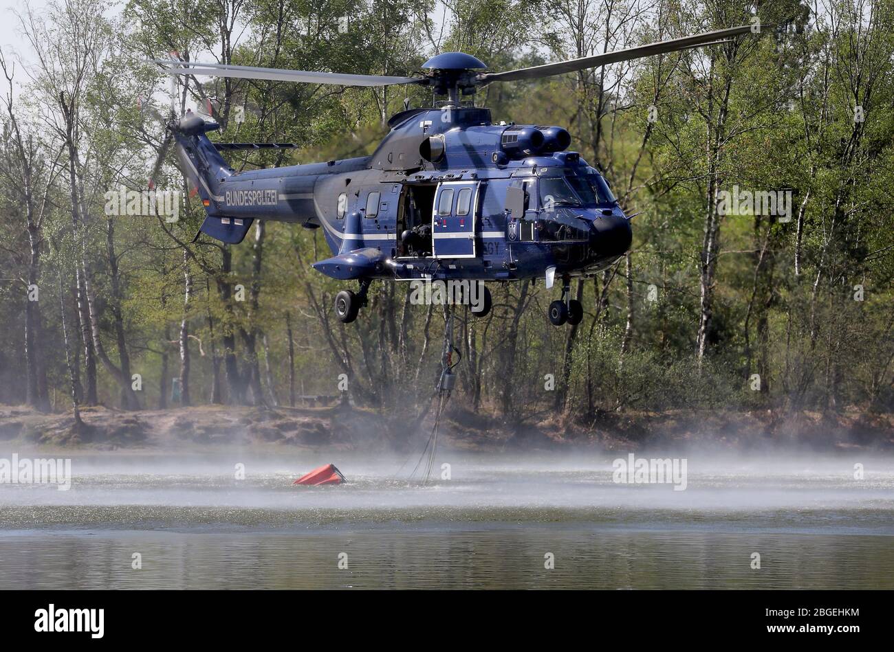 21 aprile 2020, Renania settentrionale-Vestfalia, Brüggen: Un elicottero raccoglie l'acqua con un serbatoio esterno collegato. Un incendio grave in un parco nazionale olandese al confine con la Renania settentrionale-Vestfalia sta causando problemi ai servizi di emergenza. Un portavoce delle autorità di sicurezza della provincia di Limburgo ha detto martedì alla radio olandese che il lavoro di estinzione è reso più difficile da forti venti. Foto: David Young/dpa Credit: dpa Picture Alliance/Alamy Live News Foto Stock