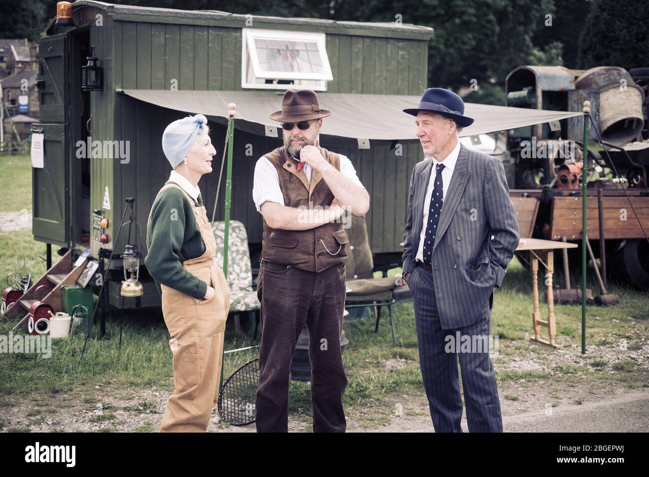 Tre persone che parlano in abiti anni '40 davanti a una carovana di legno al weekend del Pateley Bridge degli anni '40 Foto Stock