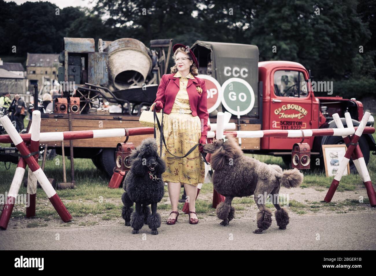 Una donna vestita con un abito glamour con stampa, con due paodle al weekend di Pateley Bridge degli anni '40 Foto Stock