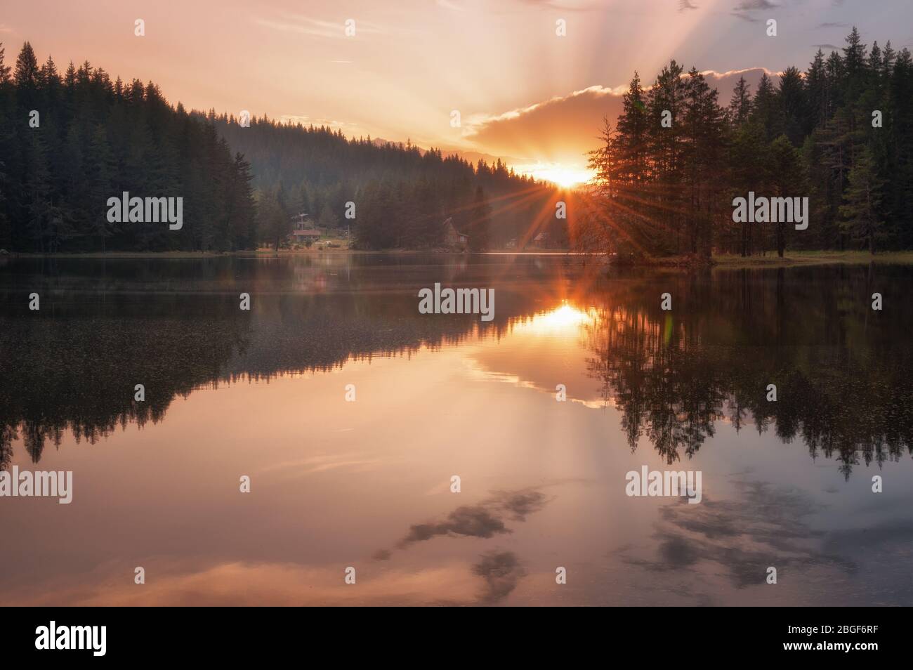 Splendida vista sul tramonto con raggi del sole su un lago di montagna. Diga di Shiroka Polyana in Rhodopi Mountains, Bulgaria. Foto Stock