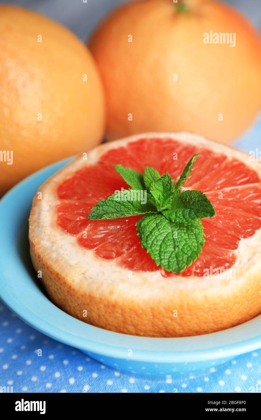 Pompelmo maturo in ciotola su sfondo di legno colorato Foto Stock