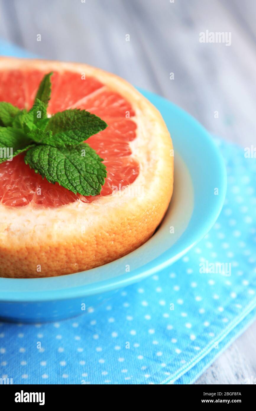 Pompelmo maturo in ciotola su sfondo di legno colorato Foto Stock