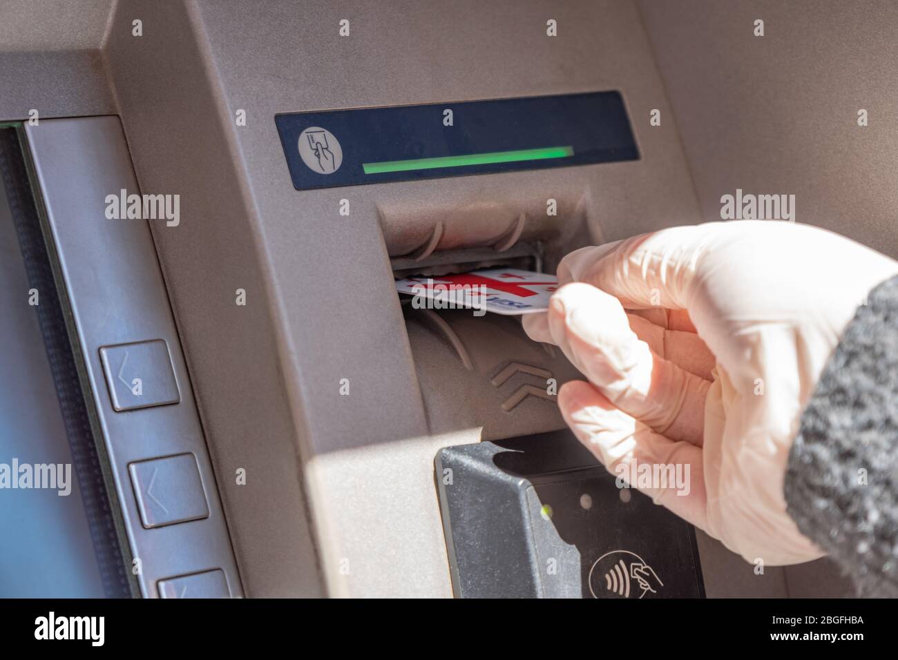 Carta bancaria Mastercard in mano in un guanto medico protettivo, ATM Foto Stock