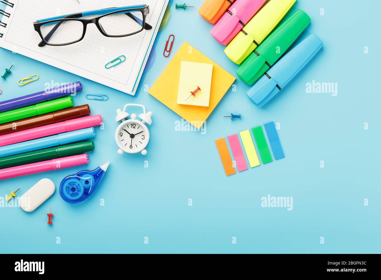I materiali per ufficio si trovano su uno sfondo blu. Per studiare a scuola. Colore arcobaleno. Spazio libero Foto Stock