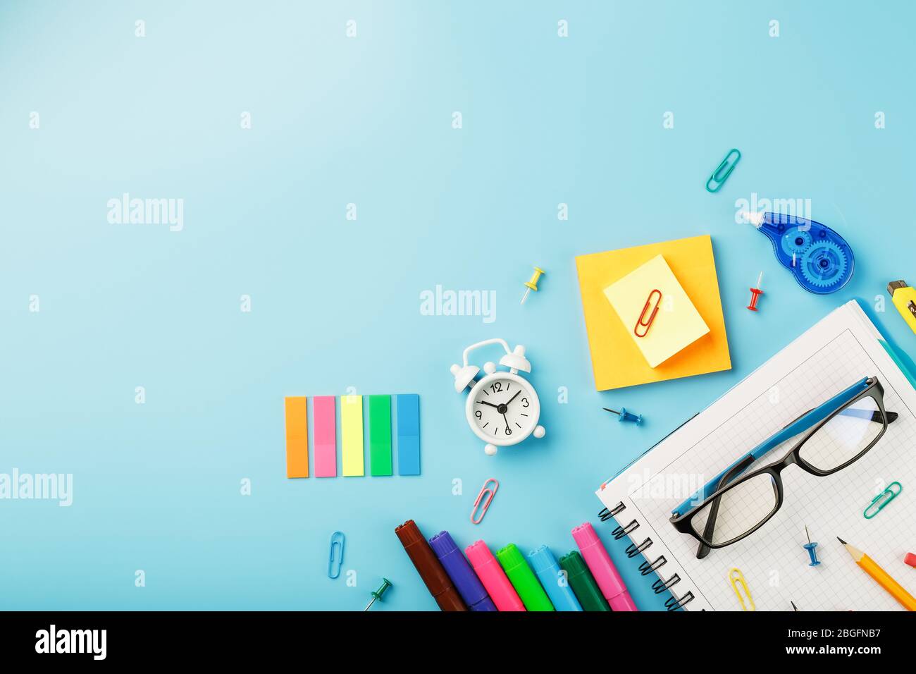 I materiali per ufficio si trovano su uno sfondo blu. Per studiare a scuola. Colore arcobaleno. Spazio libero Foto Stock