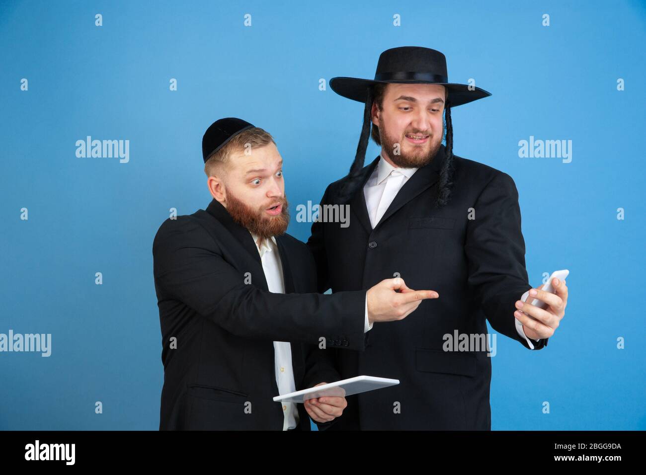 Puntamento, scelta. Ritratto di un giovane ebreo ortodosso isolato su sfondo blu studio. Purim, business, festival, vacanza, celebrazione Pesach o Pasqua, giudaismo, religione concetto. Foto Stock