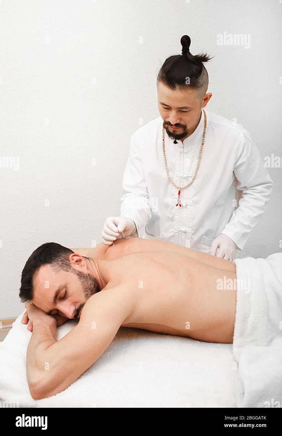 medico che fa un'agopuntura per un paziente per curare il mal di schiena cronico. Ago da vicino per l'agopuntura nella schiena dell'uomo Foto Stock