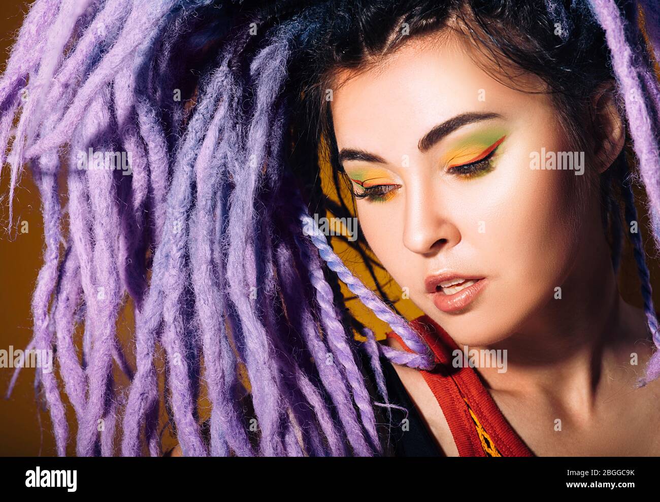 donna ritratto con lucchetti viola e trucco colorato. Stile, acconciature e trucco Foto Stock