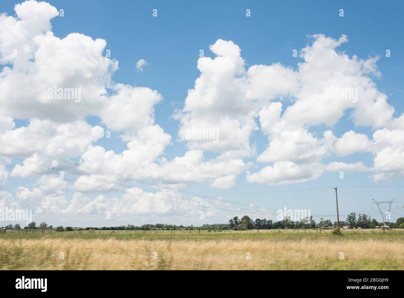 Paesaggio stradale, estate, cielo blu e nuvole bianche, linee elettriche e tralicci Foto Stock