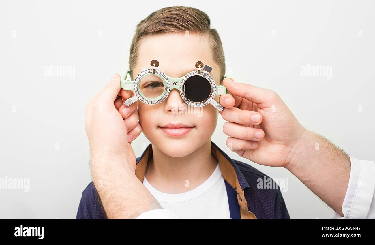 Optometrista indossare gli occhiali speciali del ragazzo per ripristinare l'acuità visiva. Trattamento con ambliopia in clinica oftalmologica Foto Stock