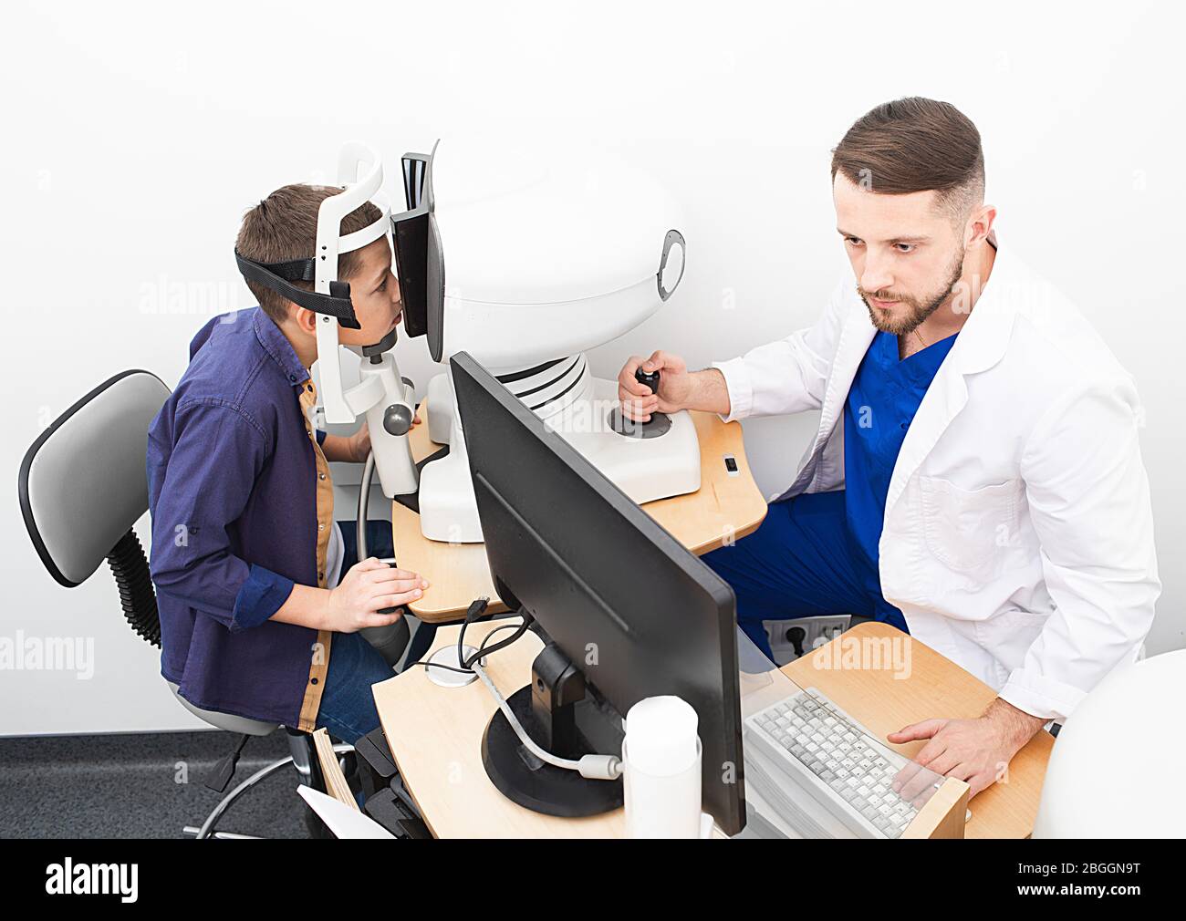 Medico di optometristo che fa con attenzione diagnosi degli occhi del bambino. Metodi moderni di diagnosi e trattamento della vista Foto Stock