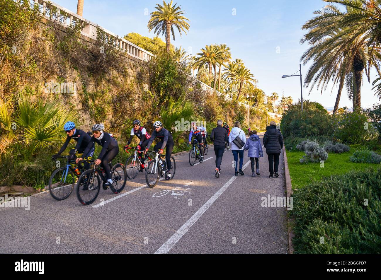 Gruppo di ciclisti, corridori e altre persone che camminano sulla pista ciclabile e pedonale della Riviera di Ponente in una giornata di sole, Imperia, Liguria, Italia Foto Stock