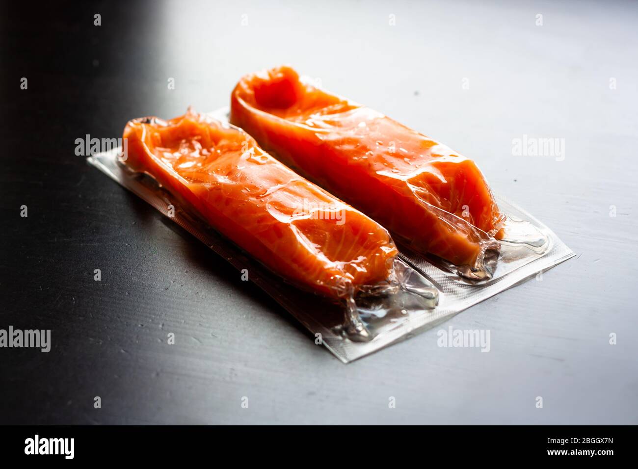Filetti di pesce rosso o salmone in confezione sottovuoto su fondo nero. Pesce fresco . Omega-3. Primo piano. Messa a fuoco selettiva. Foto Stock