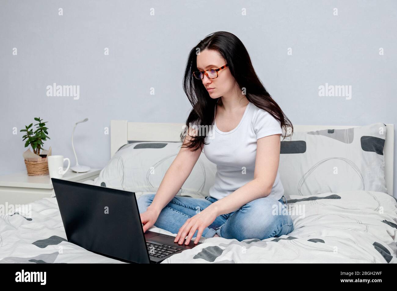 Lavoro a casa o a distanza Online Learning su Quarantune. Donna in occhiali che lavora a distanza sul letto utilizzando il laptop Foto Stock