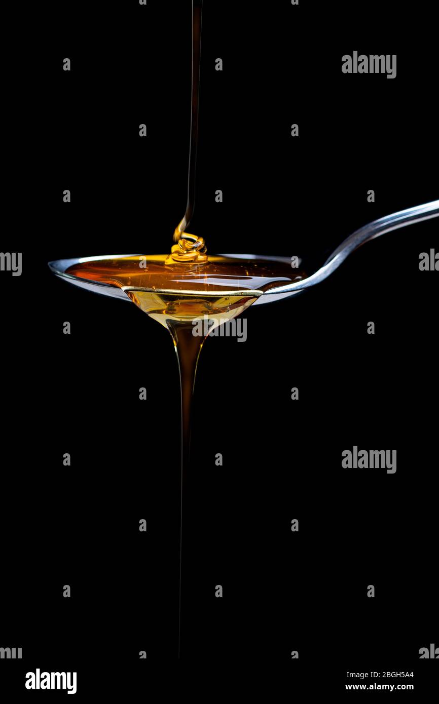 miele fresco che si versa su un cucchiaio Foto Stock