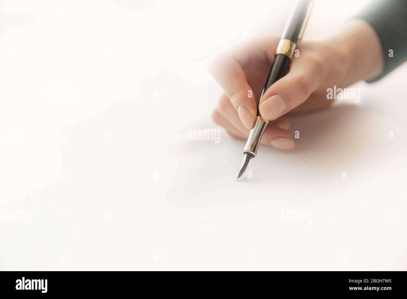 Giovane scrittore donna scrive poesia con penna fontana su foglio di carta, luce solare calda Foto Stock