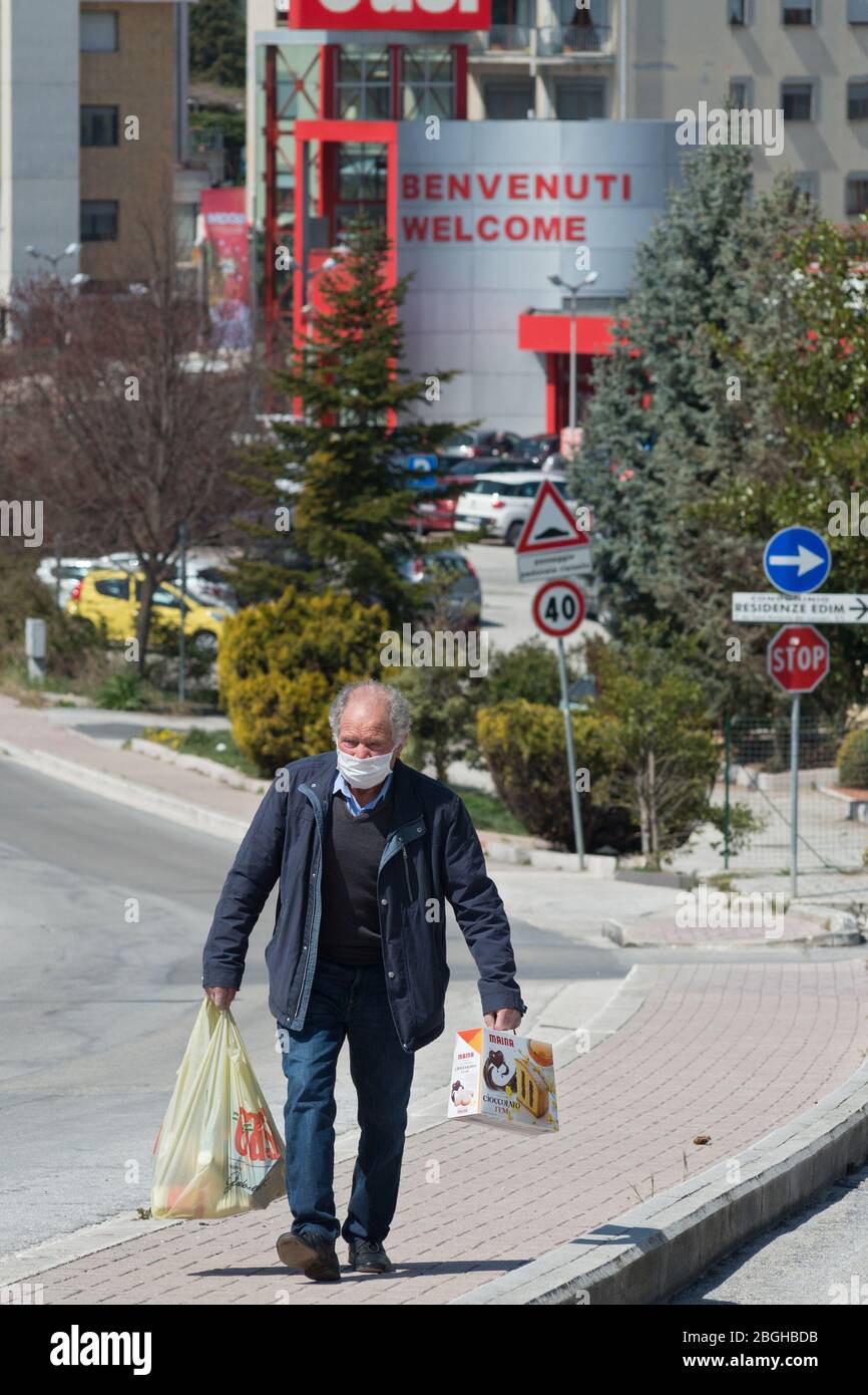 Campobasso, Regione Molise, Italia: Una persona anziana, con maschera protettiva, ritorna a casa dopo aver fatto shopping al supermercato durante il coronavirus emerg Foto Stock