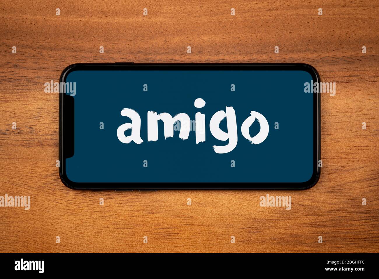 Uno smartphone che mostra il logo Amigo Loans poggia su un tavolo di legno (solo per uso editoriale). Foto Stock