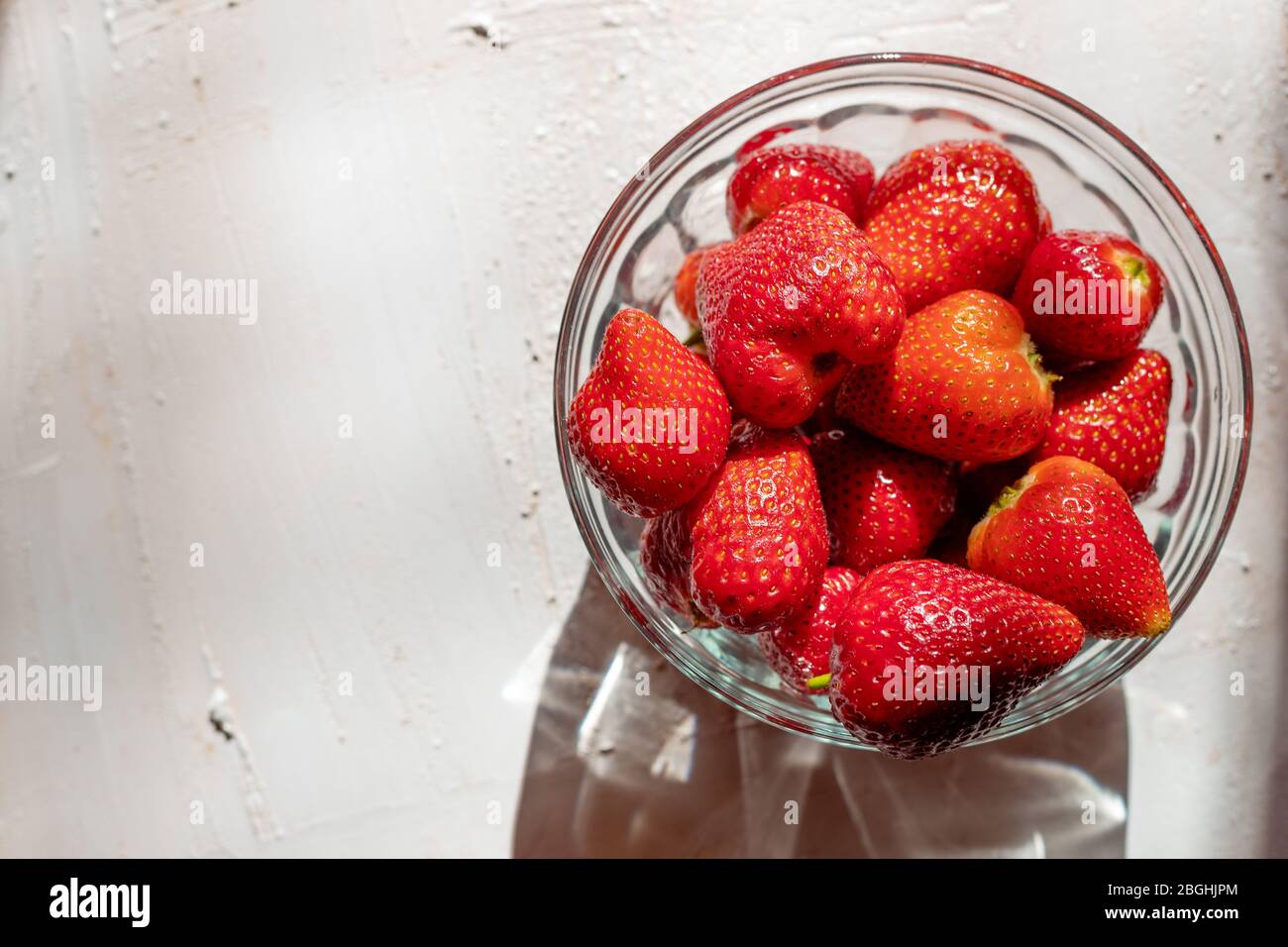 Fragole in una ciotola di vetro. Frutta aromatica. Dessert sano. Sfondo luminoso. Foto Stock