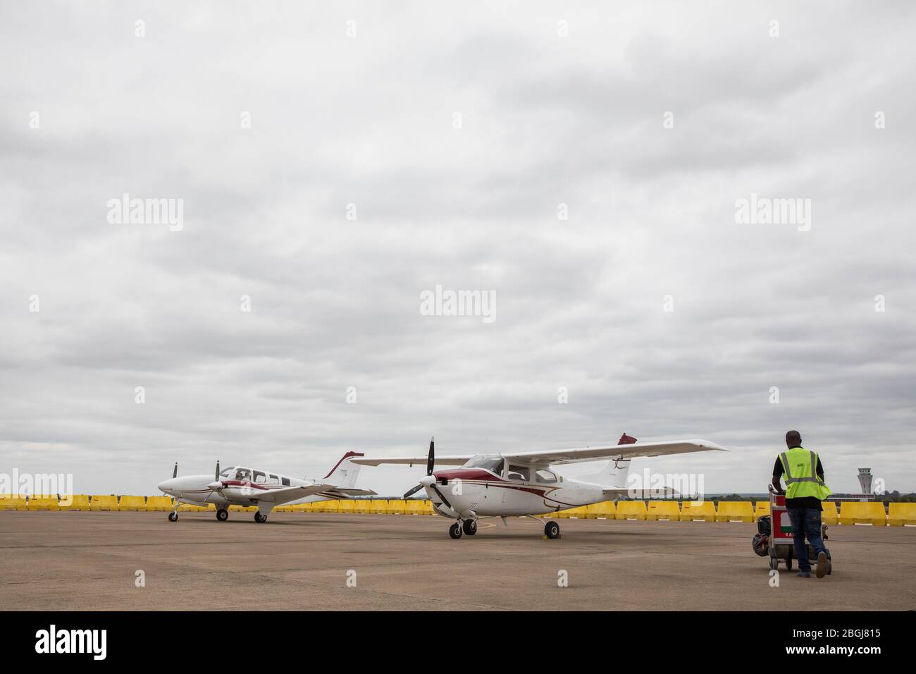 Un gestore di bagagli porta i bagagli a un piccolo aereo per un safari dall'aeroporto di Lusaka, provincia di Lusaka, Zambia. Foto Stock