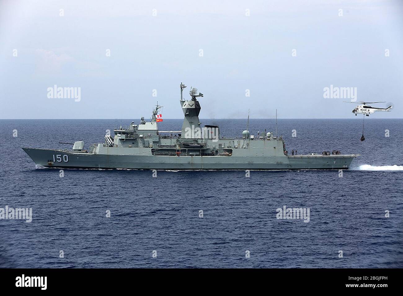 HMAS Anzac durante un'operazione di rifornimento verticale con un elicottero statunitense nel 2016. Foto Stock