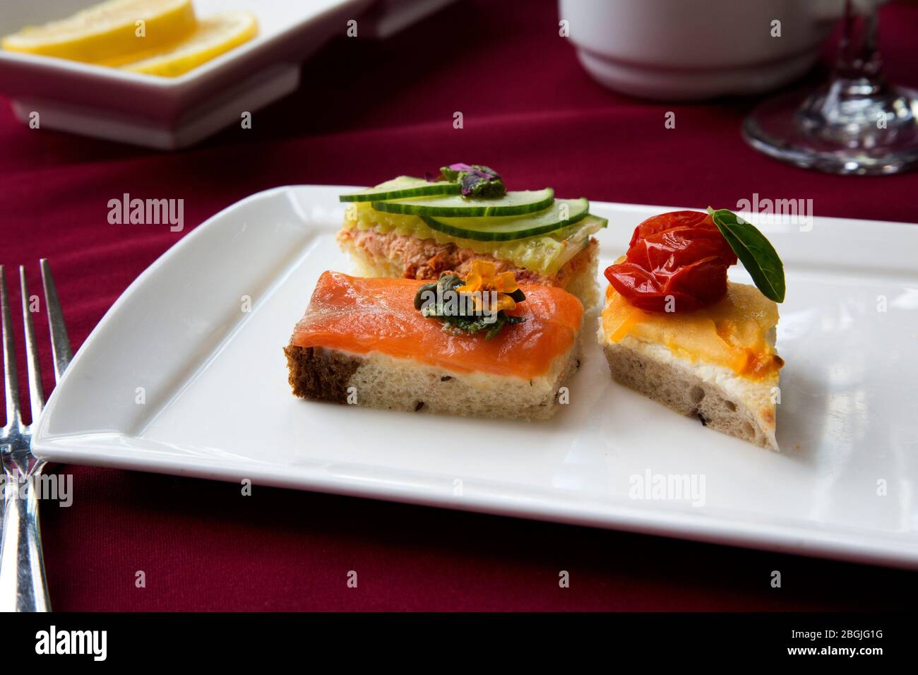 Su un piatto bianco sono collocati gustosi e ben guarniti panini con salmone, insalata di pollo e pomodori arrostiti Foto Stock