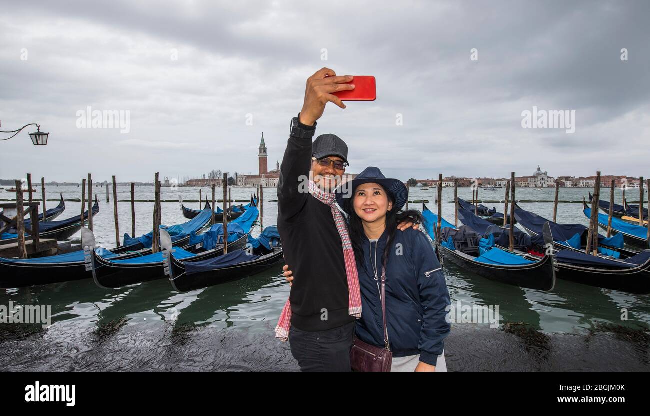 Coppia tailandese che prende selfie di fronte alla gondola parcheggiata a Venezia Foto Stock