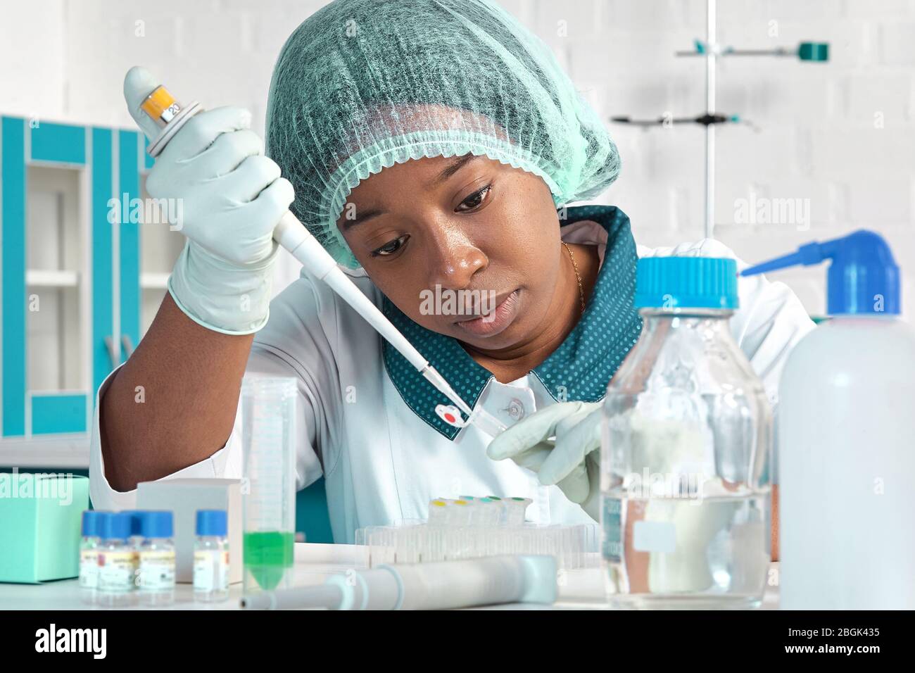 Scienziato africano, assistente tecnico o tecnico medico in cappotto bianco, cappello protettivo e guanti ottimizza i test PCR per il virus SARS-cov-2 in MO Foto Stock