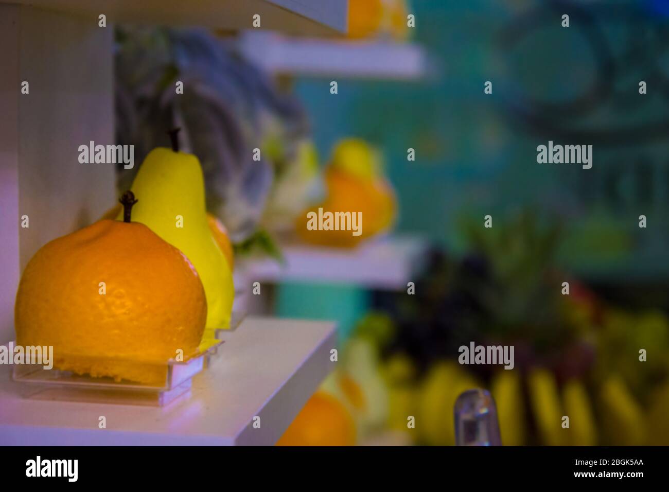 Dolce arancia cuoca con frutta forma un ripiano accanto ad altri frutti meno visibile in bokeh sullo sfondo Foto Stock