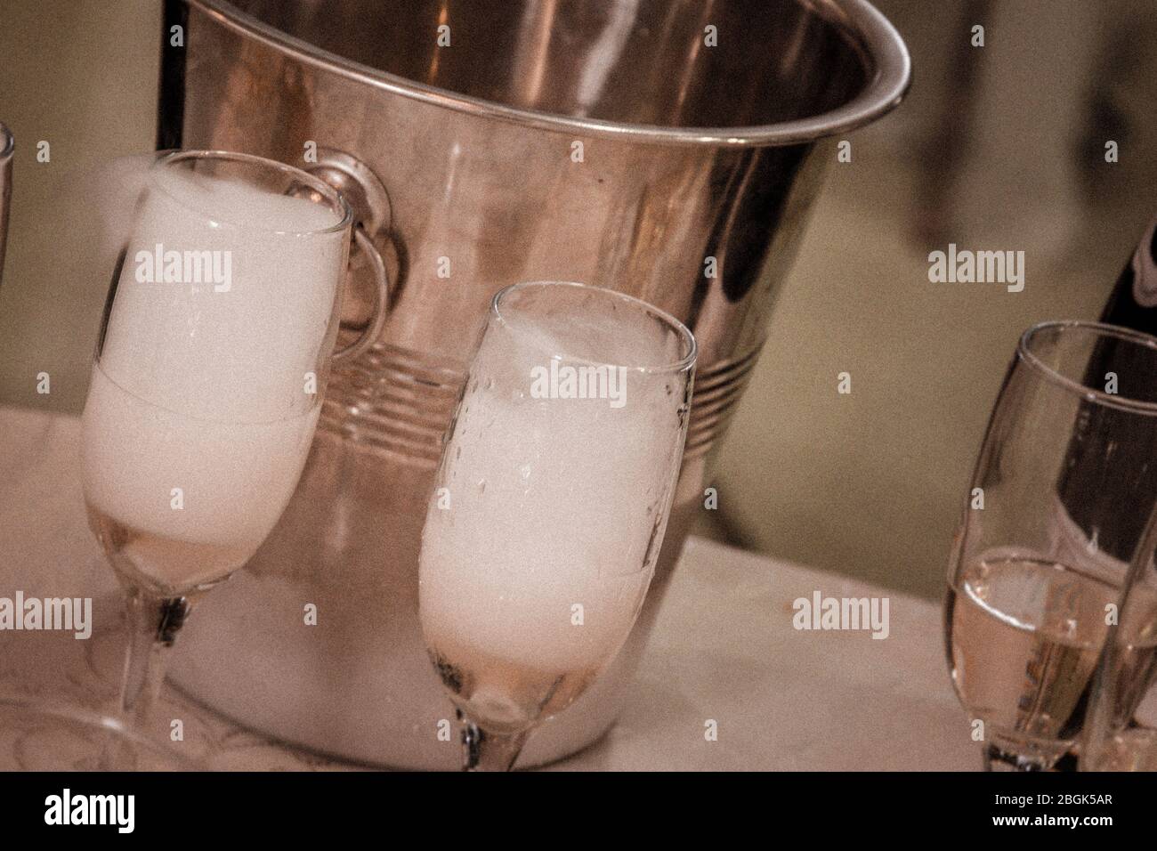 Due bicchieri di champagne pieni di bevande e schiuma in tonalità seppia inclinata a destra Foto Stock