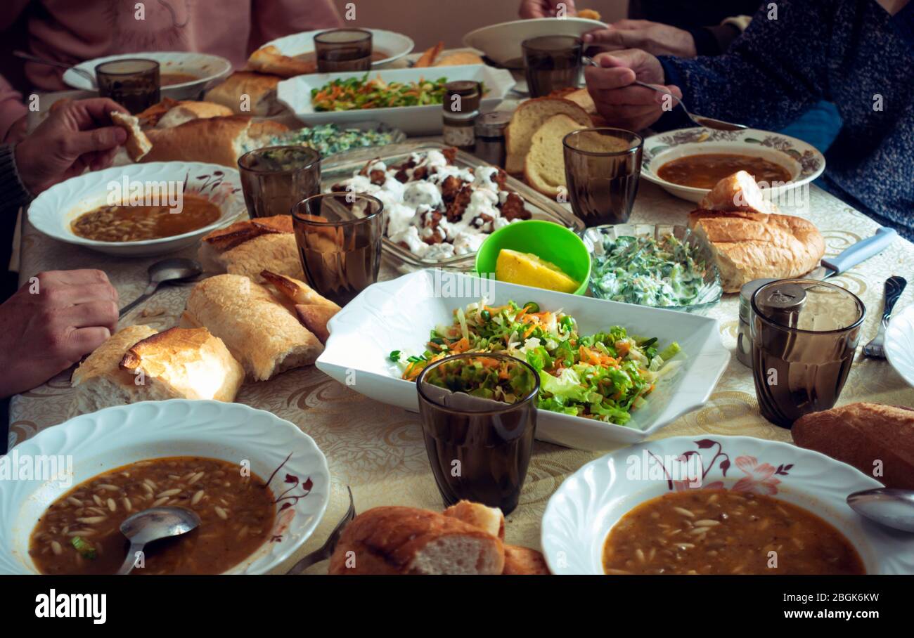 Affollata famiglia musulmana che ha iftar in un giorno ramadan con un tavolo pieno di deliziosi piatti vegani cercando Foto Stock