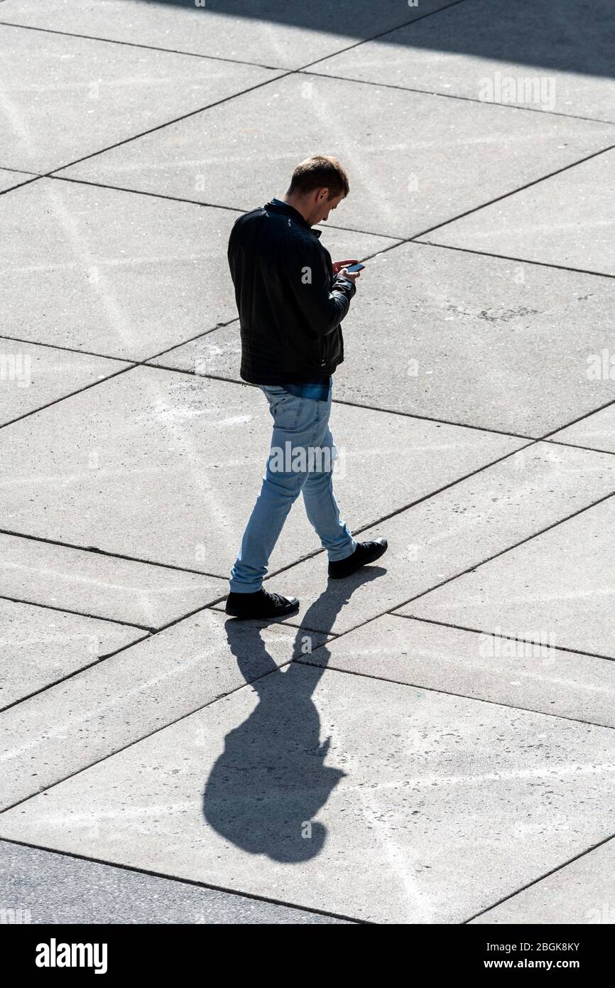 Uomo che guarda lo smartphone mentre cammina Foto Stock