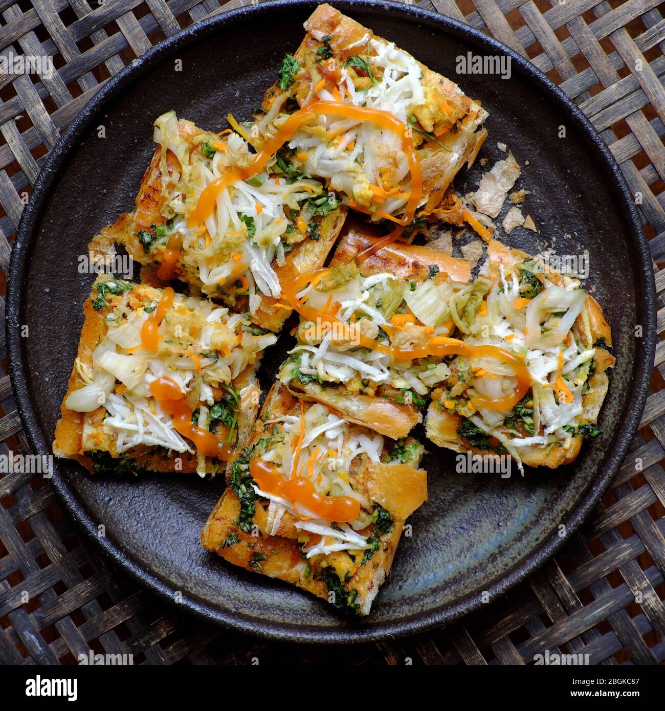 Delizioso cibo vegano pronto a mangiare per colazione, piatto di pane tostato a fette, pane vegetariano vietnamita con verdure per dieta non a base di carne su nero Foto Stock